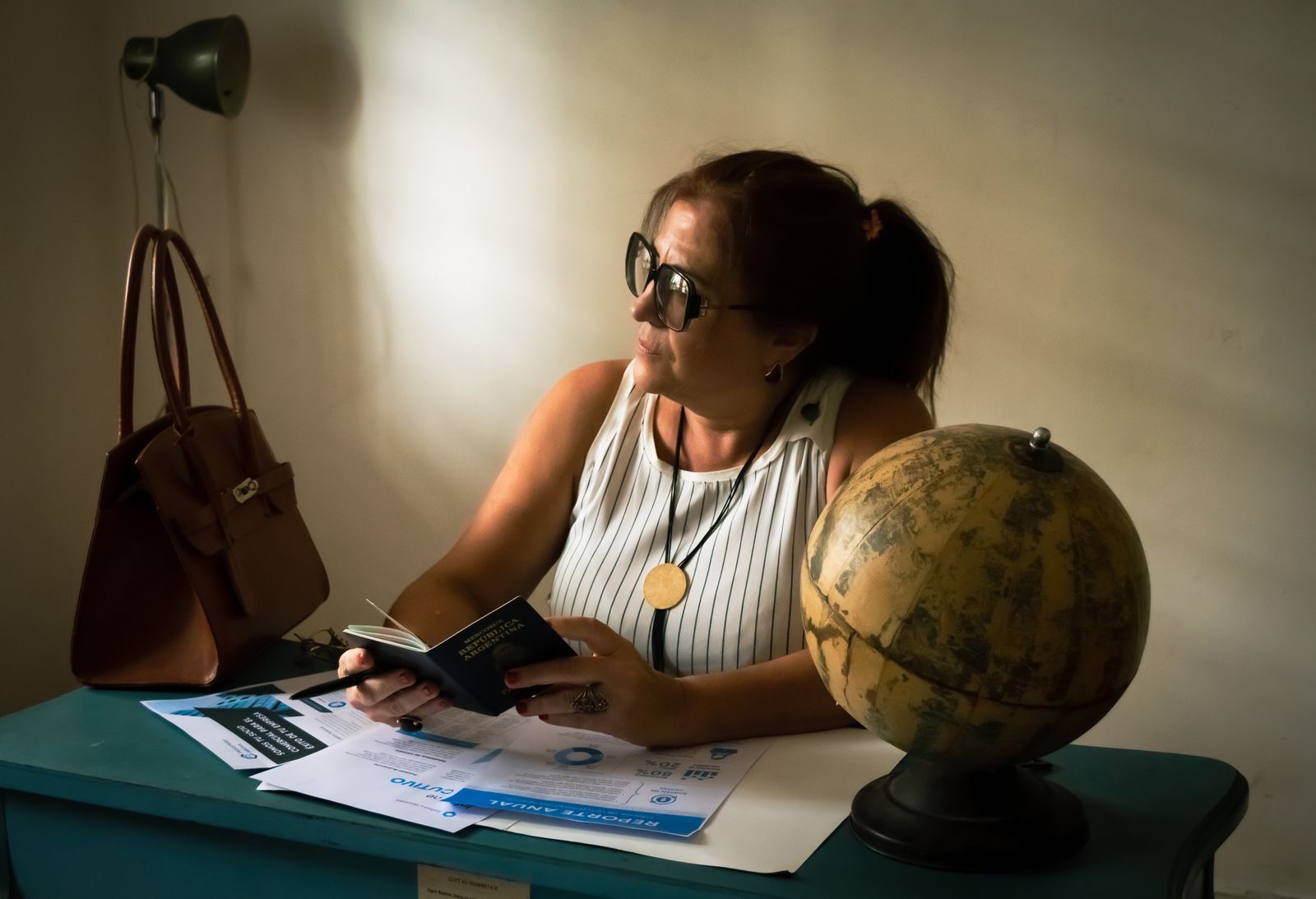 A company director signing registration forms at a desk beside a passport, preparing the KVK file for a Dutch branch.