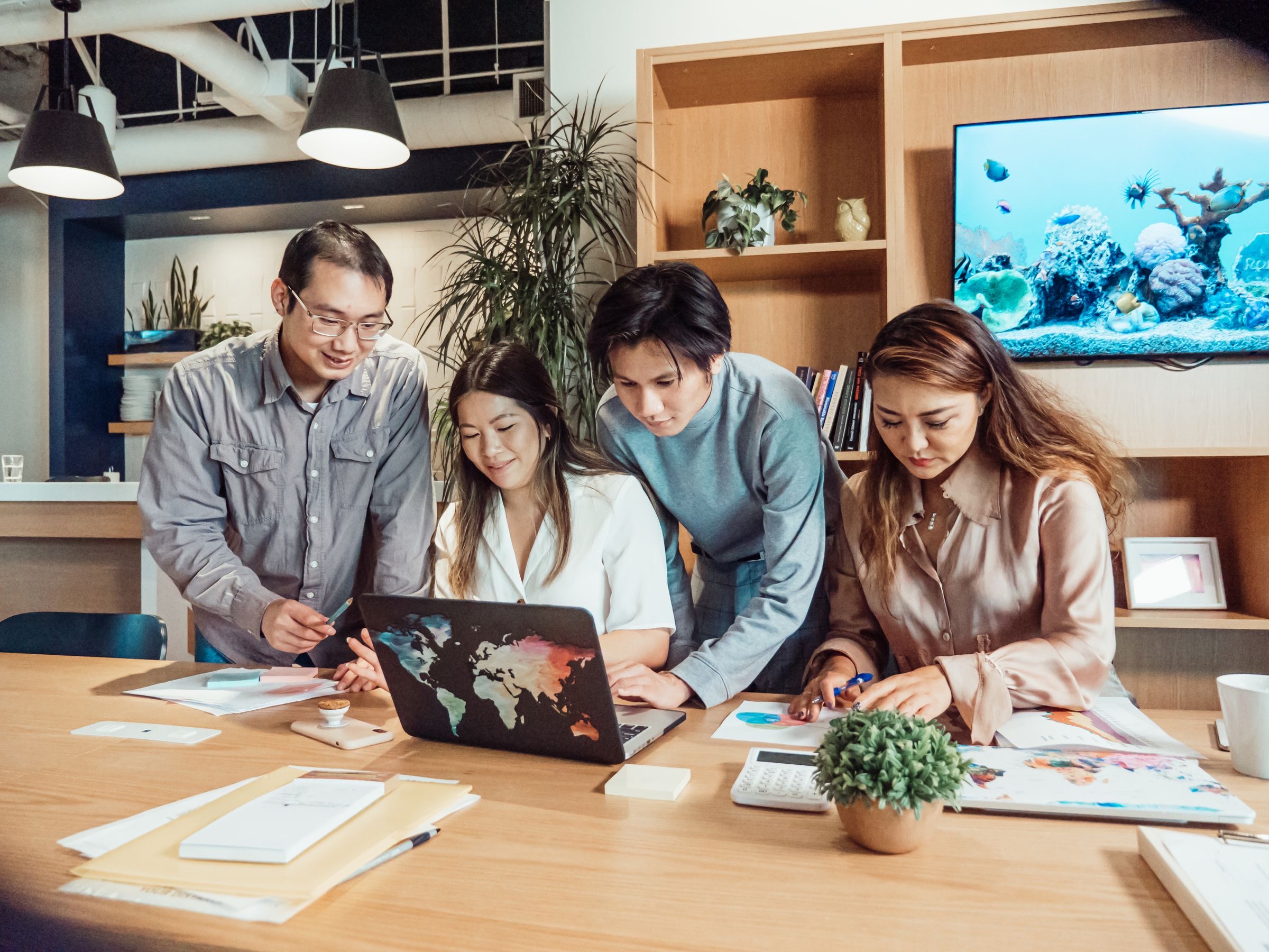 A small fintech team reviewing compliance documents at a laptop while preparing a crypto licence application.