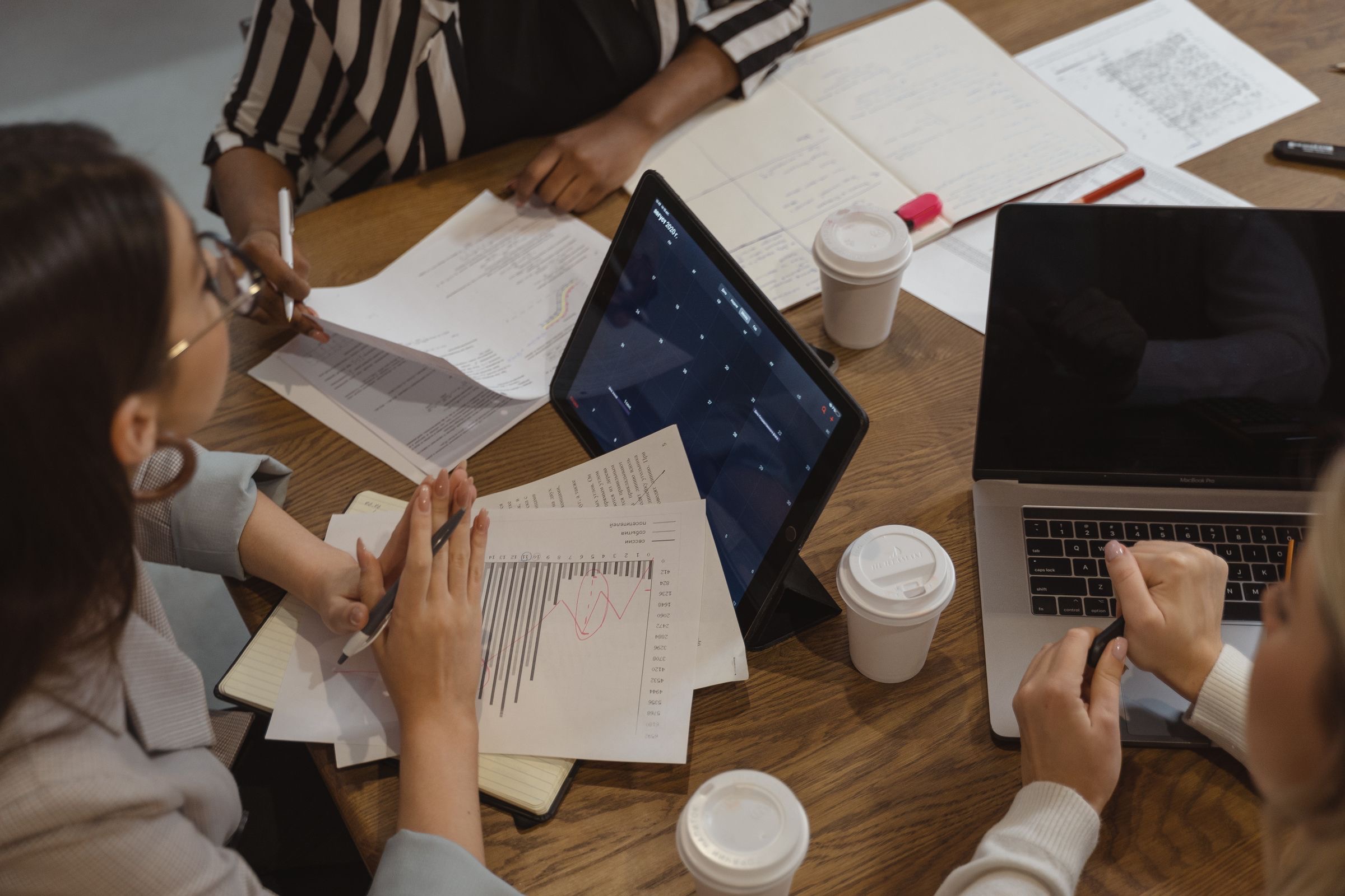 A small foundation board around a table, reviewing printed draft articles.