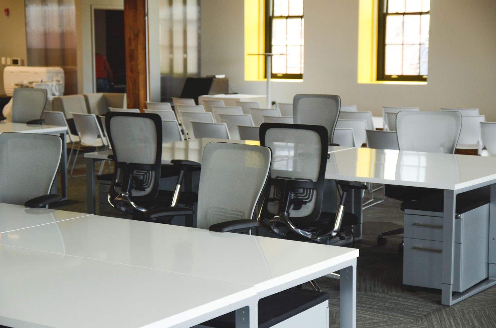 An empty office chair at a tidy desk in a small shared office