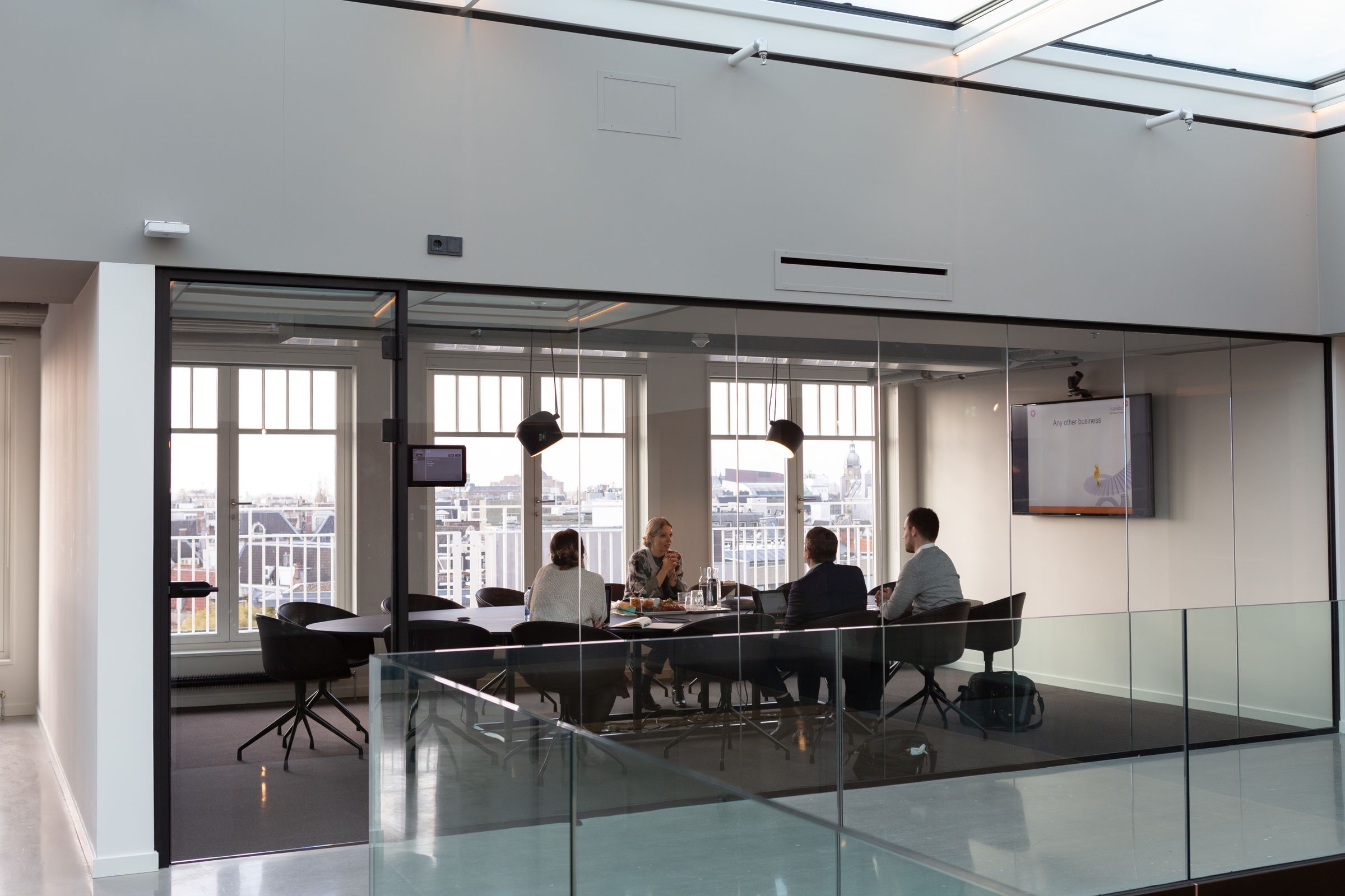 An international management team meeting around a boardroom table in an Amsterdam office to plan a Dutch subsidiary.
