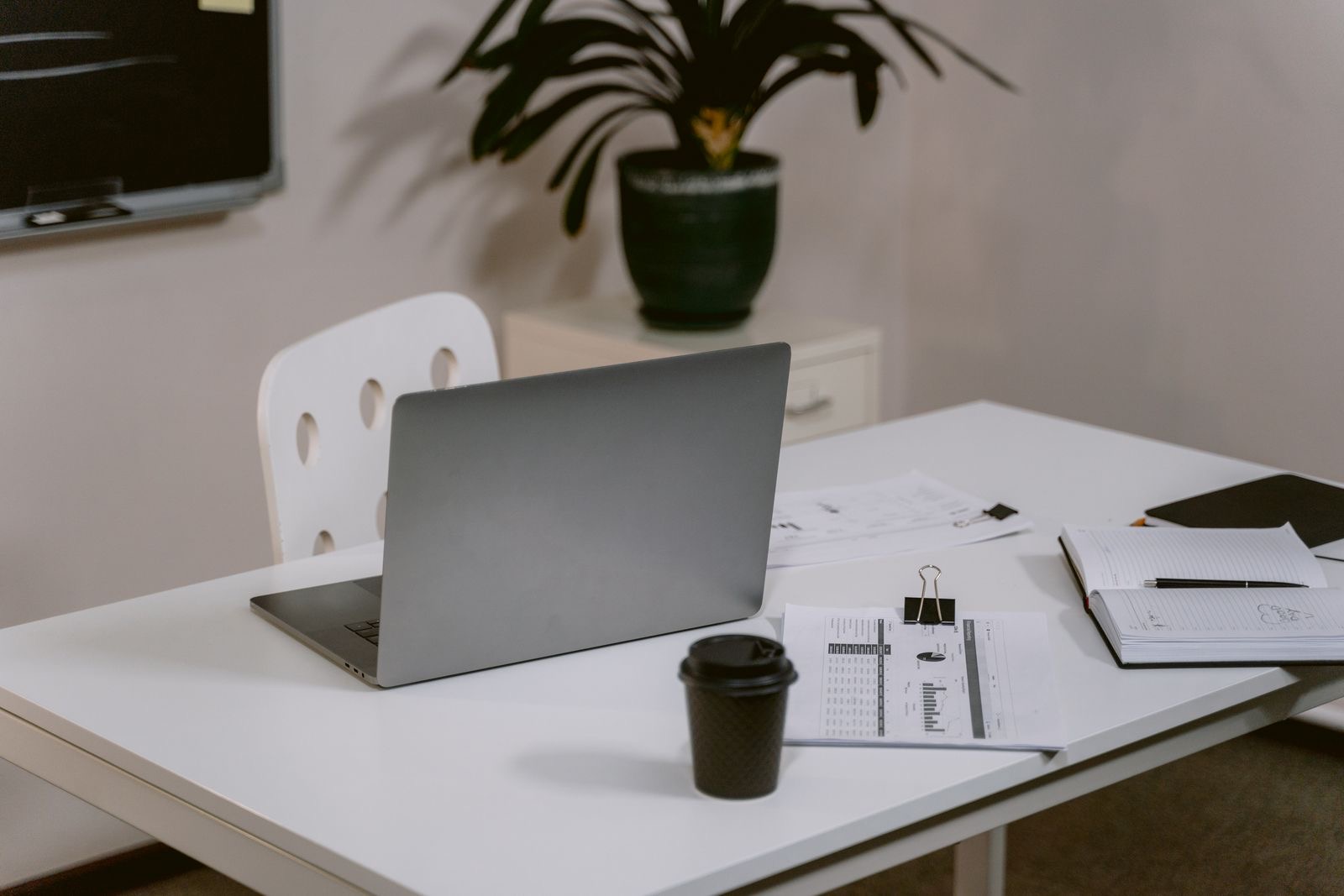 Binders and a laptop on a desk with policy documents for a payment institution licence application file.