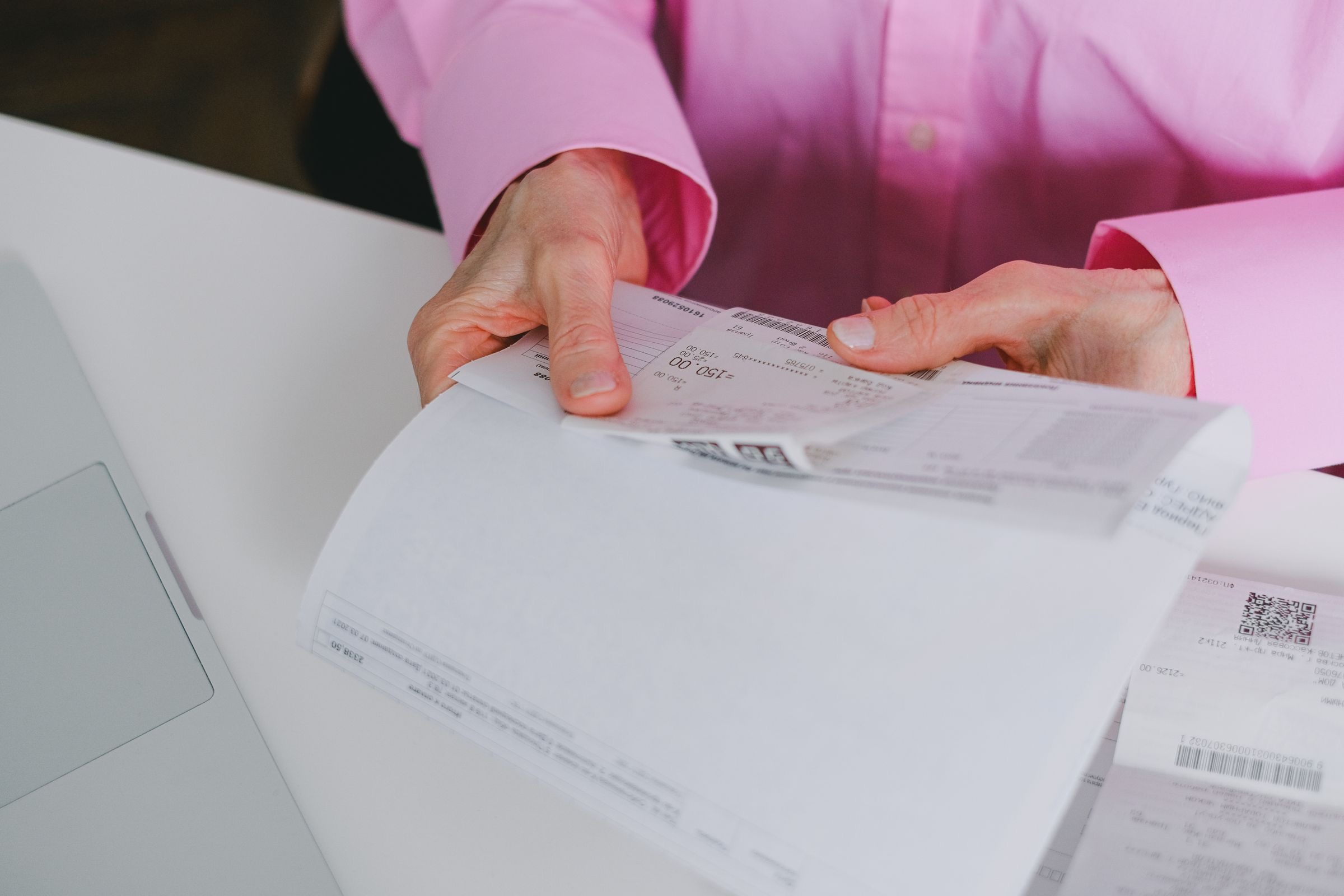 A company owner abroad reviewing invoices and correspondence at a laptop before registering the business for Dutch VAT.